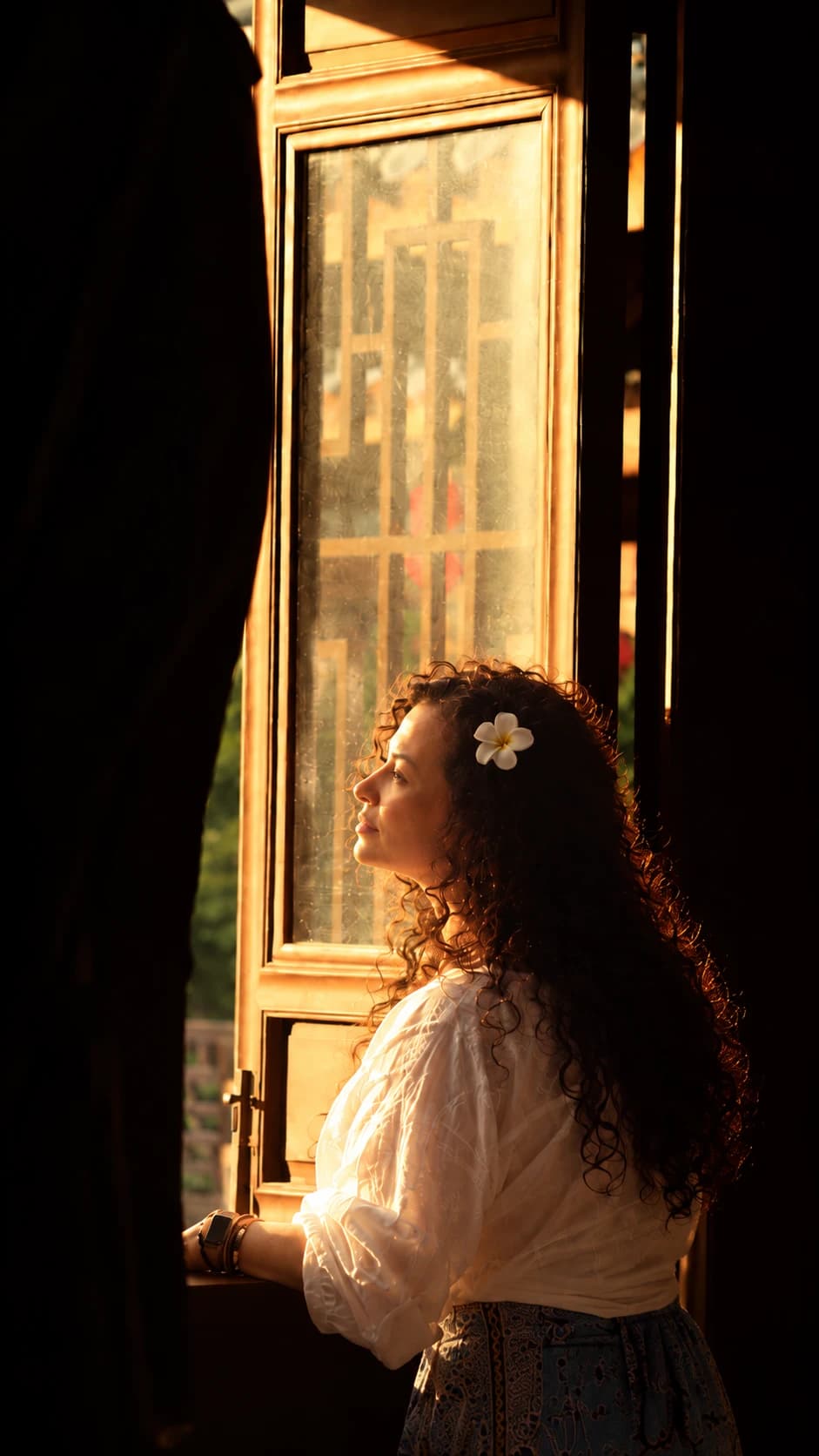 Una mujer haciendo una pausa junto a una ventana iluminada, en reflexión silenciosa